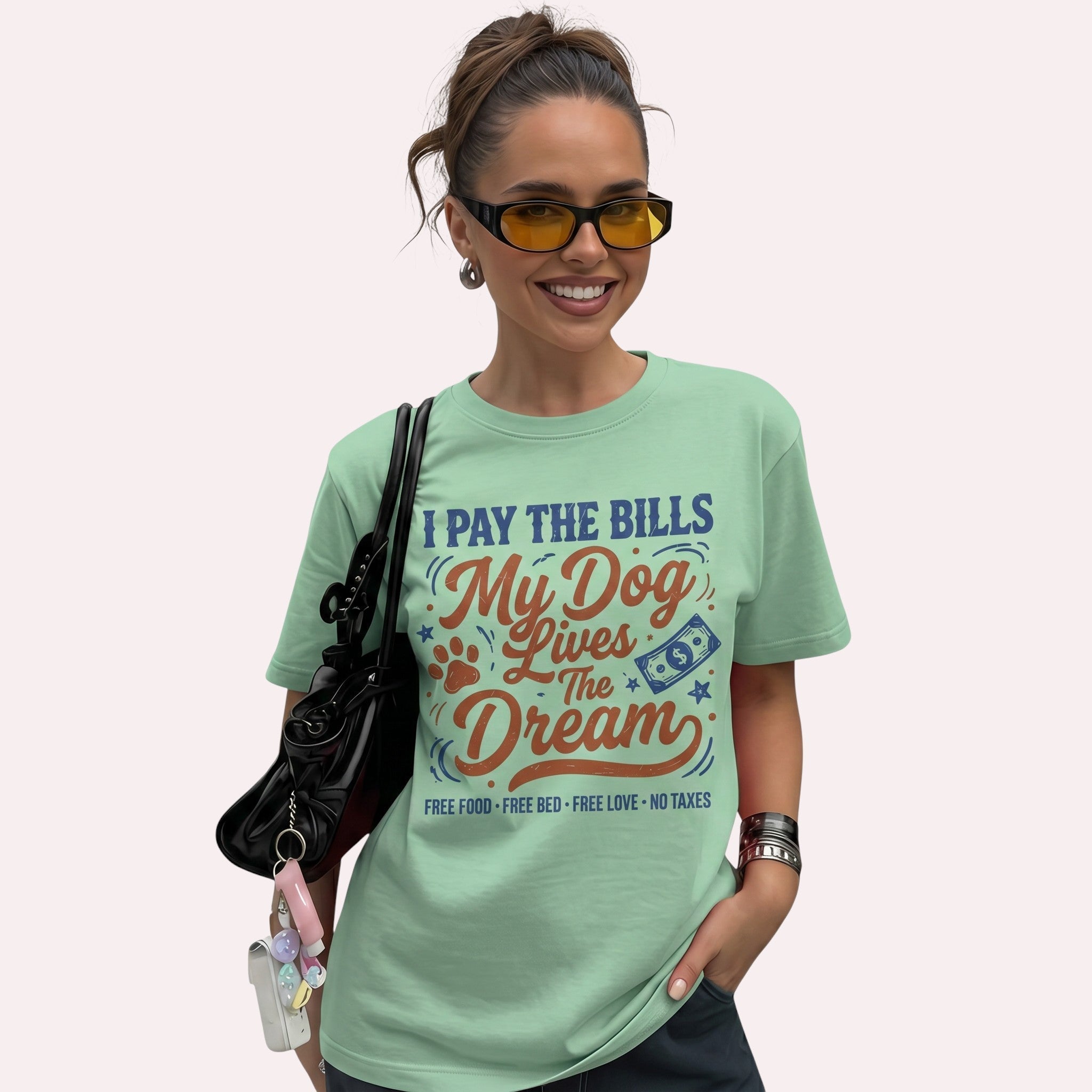 TrendyShift.Com light green cotton t-shirt featuring I Pay The Bills My Dog Lives The Dream graphic on a smiling woman.