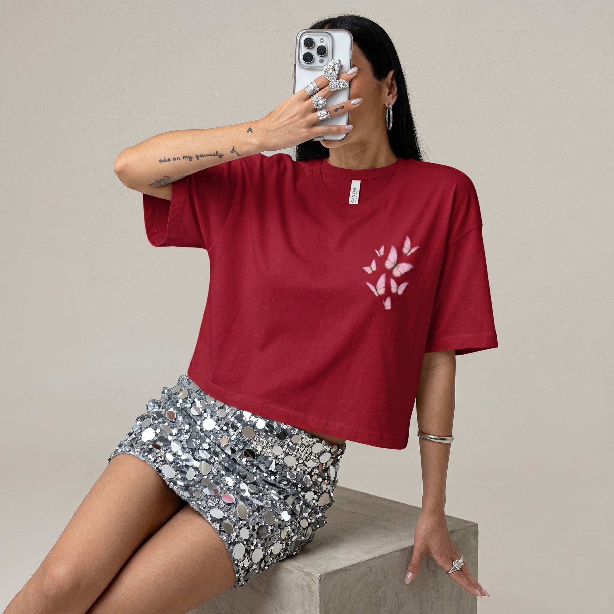 TrendyShift.Com cropped red t-shirt with pink butterfly graphic, worn with a sequin mini skirt by a woman holding a phone